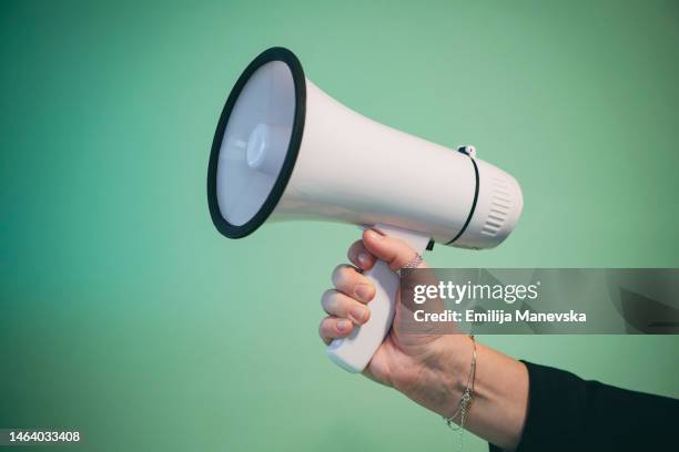 cropped hand of woman holding megaphone - altavoz fotografías e imágenes de stock