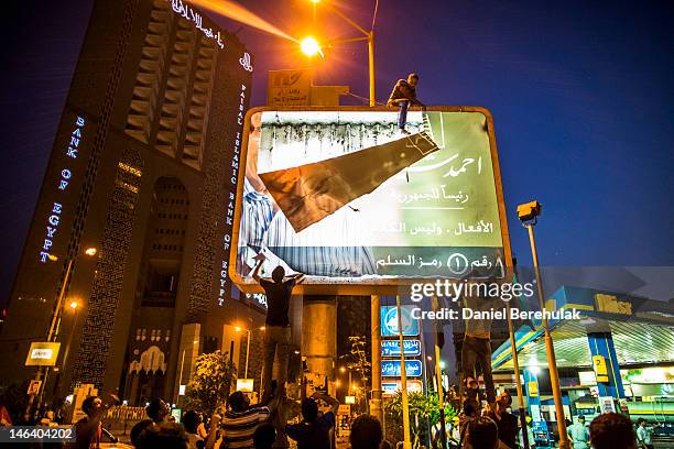 Egyptians protestors climb a billboard and pull down a poster of presidential candidate Ahmed Shafiq as they march to protest in Tahrir Square on...