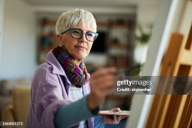 mature female painter enjoying while painting in art studio. - old spectacles stock pictures, royalty-free photos & images