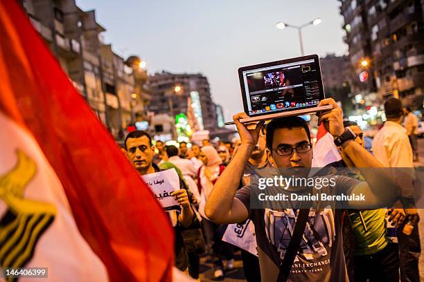 Protestor walks with a laptop on his head, streaming live during a demonstration against presidential candidate Ahmed Shafiq and the Supreme...