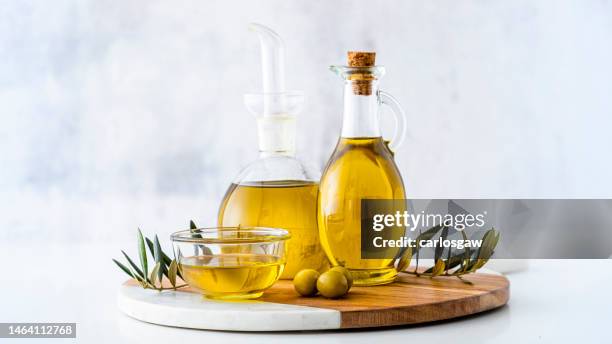 tres botellas de aceite de oliva aisladas en una mesa de cocina - aceitera fotografías e imágenes de stock