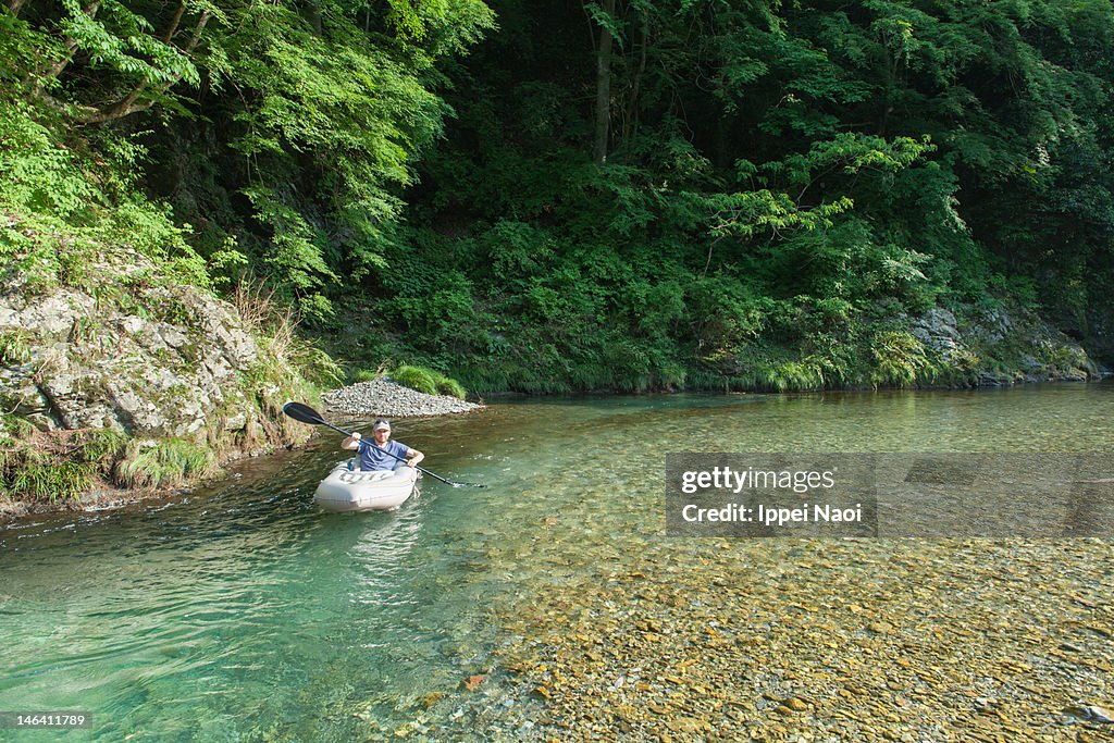 Paddling on clear water of forest river, Japan