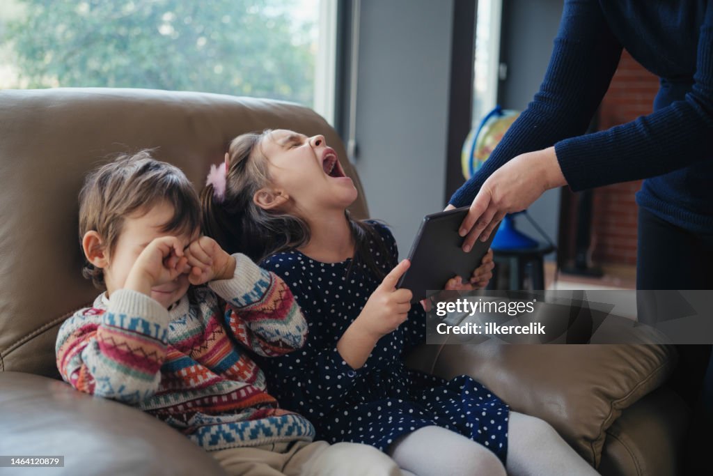 Mutter verbietet ihrer Tochter und ihrem Sohn, Spiel auf digitalem Tablet zu spielen, Konzept für Abhängigkeit von Gadgets