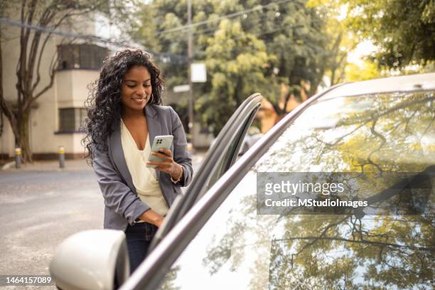 ユーバーのドアを開けながら電話を持つ若い女性 - yellow taxi ストックフォトと画像