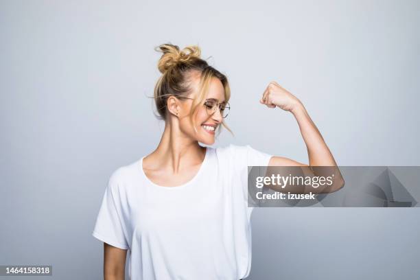 feliz mujer hermosa flexionando músculo - armas de mujer fotografías e imágenes de stock