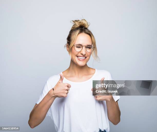 lächelnde frau zeigt daumen hoch, während sie zwinkert - happy woman thumbs studio stock-fotos und bilder