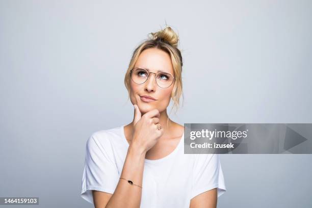 mujer pensativa con la mano en la barbilla mirando hacia arriba - ideas fotografías e imágenes de stock