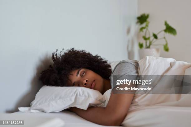 young african woman sleeping in her bed in the morning - dormir fotografías e imágenes de stock