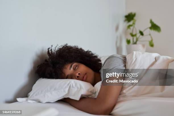young african woman sleeping in her bed in the morning - slapen stockfoto's en -beelden