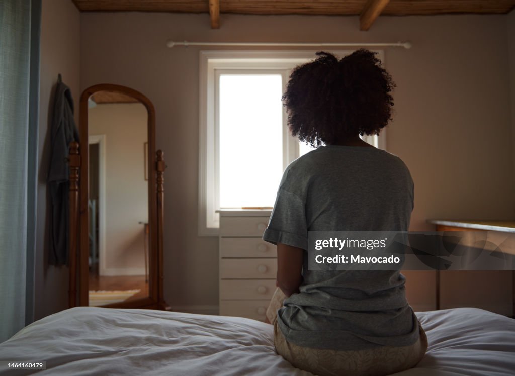 Young African woman suffering from depression sitting in her bedroom
