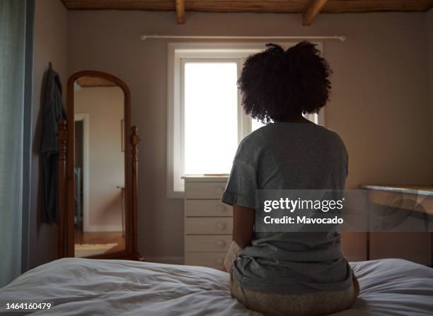 young african woman suffering from depression sitting in her bedroom - loneliness stock pictures, royalty-free photos & images