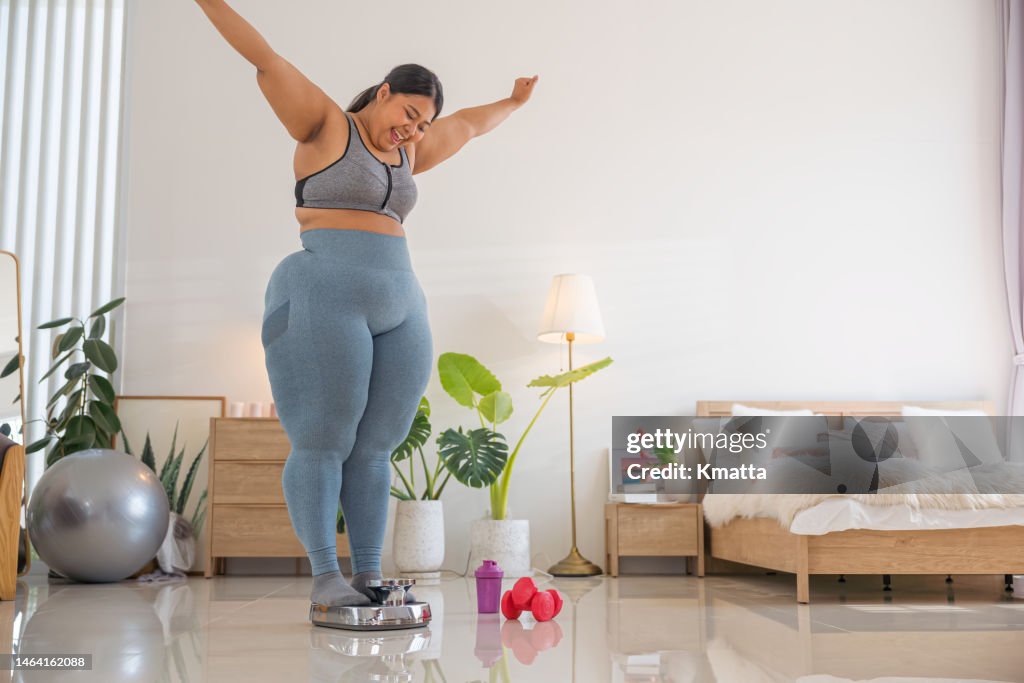 Plus size woman weighing herself on a scale. Success to loss weight.