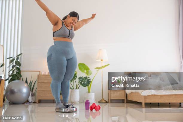 plus size woman weighing herself on a scale. success to loss weight. - fat loss training stockfoto's en -beelden