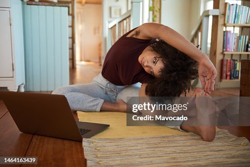 Young African woman stretching during an online yoga class at home Young African woman stretching during an online yoga class at home