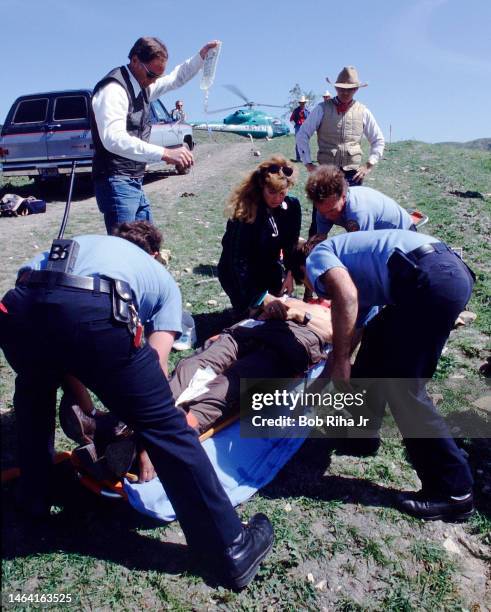 Orange County Sheriff Brad Gates holds an IV bag while assisting Paramedics and LIFEFLIGHT Air Team Medics while transporting an individual who was...