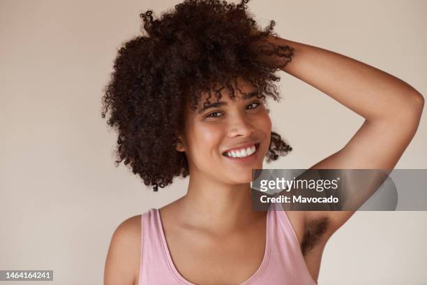 smiling young african woman with armpit hair standing on a light background - armpit hair woman stock pictures, royalty-free photos & images