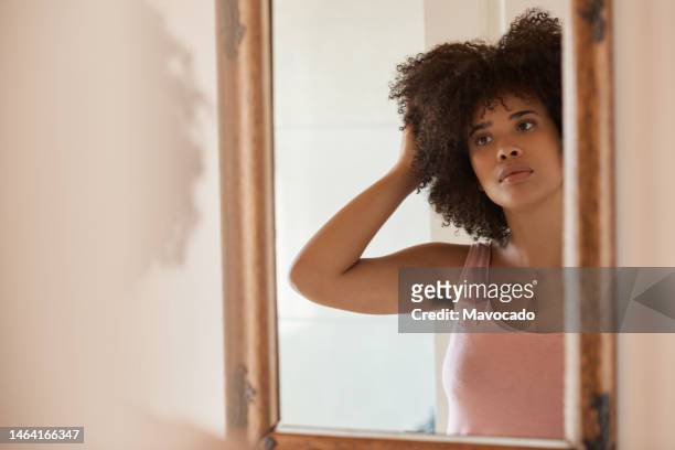 young african woman looking at her hair in mirror in the morning - behaart stock-fotos und bilder