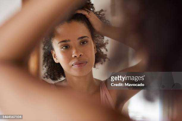 smiling young african woman looking at her complexion in a bathroom mirror - armpit hair woman stock pictures, royalty-free photos & images