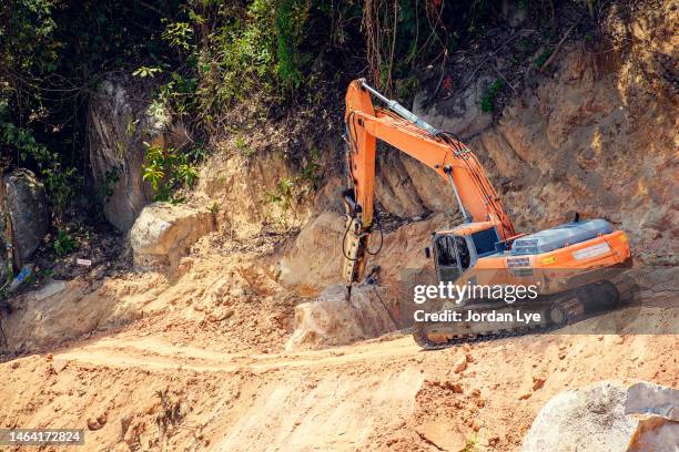 excavator drilling on top of rocks at infrastructure construction site - heavy demolition stockfoto's en -beelden