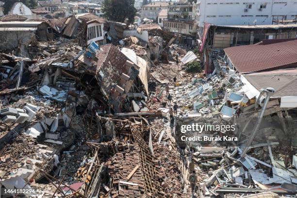 People walk past collapsed buildings on February 08, 2023 in Hatay, Turkey. A 7.8-magnitude earthquake hit near Gaziantep, Turkey, in the early hours...