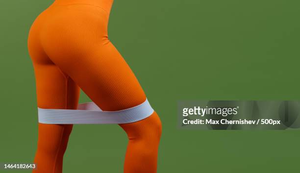 woman with expander for legs in orange fitness sport outfit cloth - maillot de sport stockfoto's en -beelden