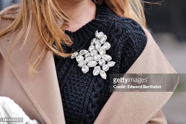 Maria Rosaria Rizzo wears a black braided wool pullover with a large crystal brooch, a beige long wool belted coat, a white sheep fur puffy handbag,...