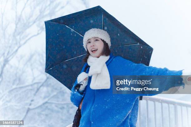 junge glückliche asiatische frau, die spaß unter regenschirm hat, während sie die berglandschaft mit schnee im winter erkundet - yamagata stock-fotos und bilder