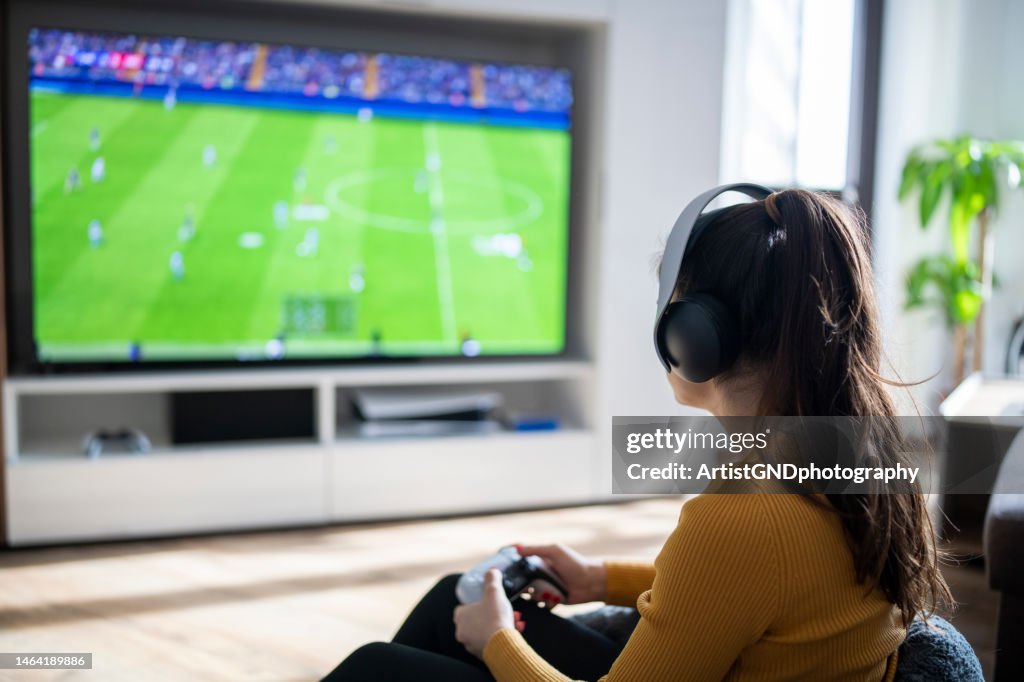 Woman playing football game on gaming console.