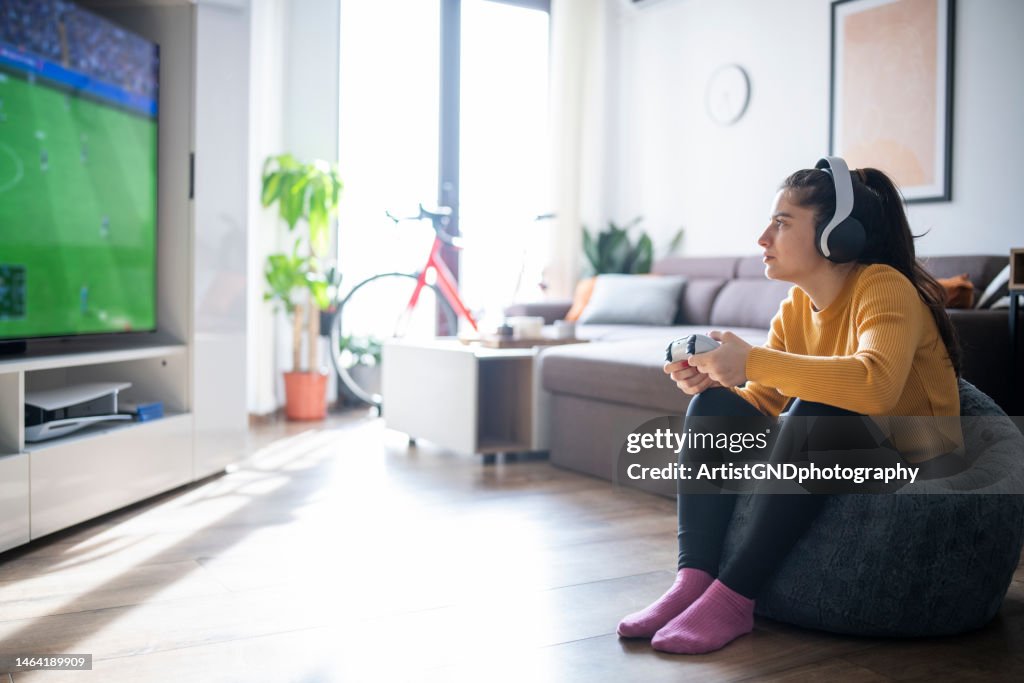 Woman playing football game on gaming console.