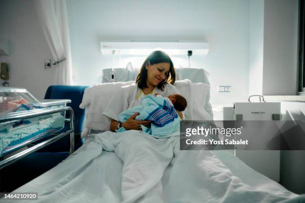 a smiling mother after breastfeeding her newborn - baby delivery stock-fotos und bilder