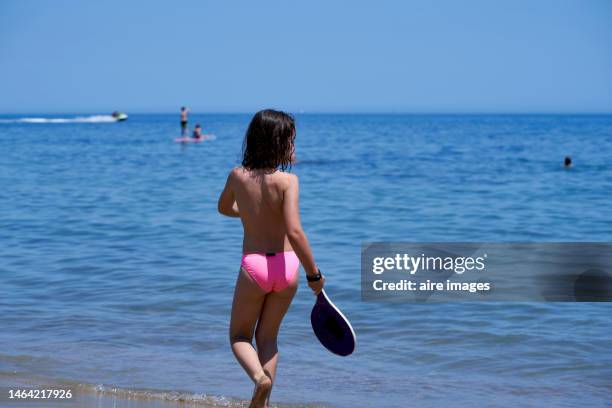 photo of the back of a brown-haired white girl playing racket ball on the shore of the beach - racketball stock pictures, royalty-free photos & images