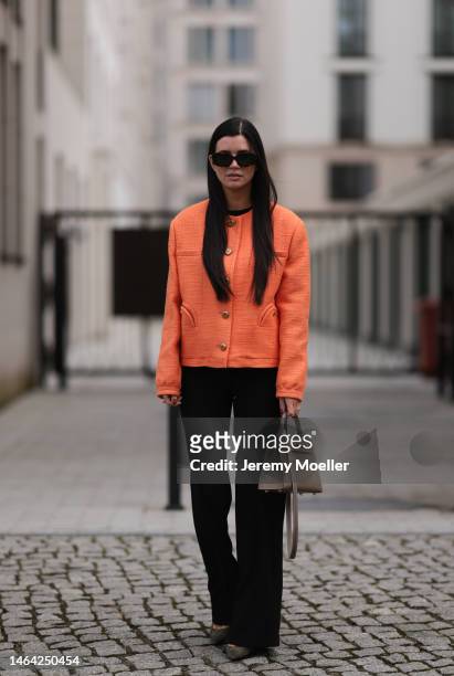 Leo Eberlin is seen wearing Zara black suit pants, Blaze Milano orange blazer, Gianvito Rossi olive leather heels, Hermes brown leather Kelly bag and...