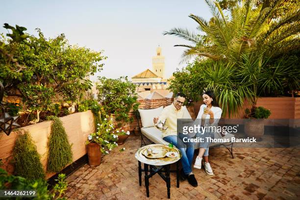 wide shot of couple having tea on rooftop of luxury hotel in marrakech - rooftop dining foto e immagini stock
