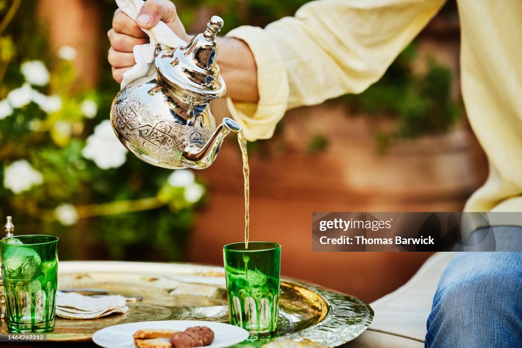 Close up shot of man pouring mint tea on rooftop deck of luxury hotel