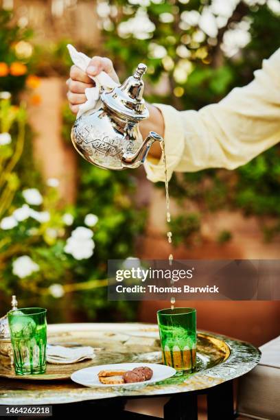 close up shot of man pouring mint tea on rooftop deck of luxury hotel - culture marocaine photos et images de collection