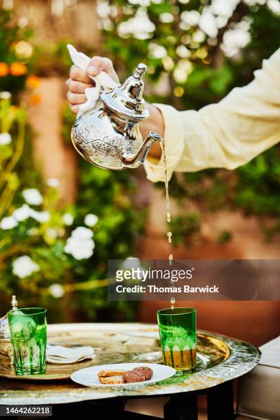 Close up shot of man pouring mint tea on rooftop deck of luxury hotel