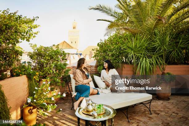 wide shot of friends relaxing in rooftop garden of luxury hotel - luogo di preghiera foto e immagini stock