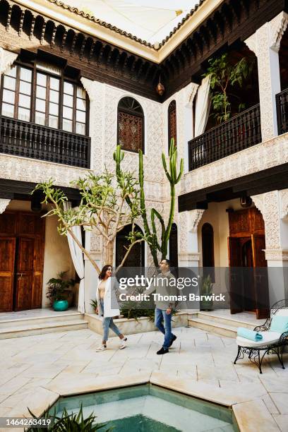 wide shot of couple walking through courtyard of luxury hotel - 33 arches stock pictures, royalty-free photos & images
