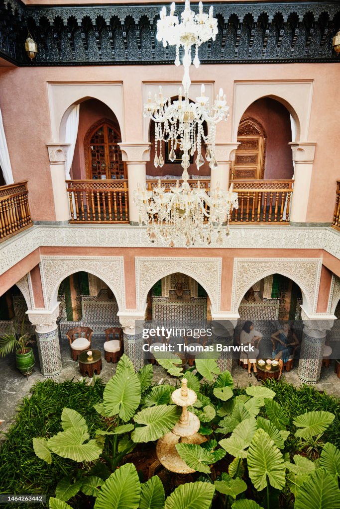 Extreme wide shot of friends relaxing in courtyard of luxury hotel