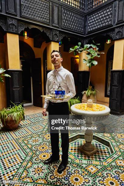 wide shot of waiter holding tea service in courtyard of luxury hotel - fountain courtyard fotografías e imágenes de stock