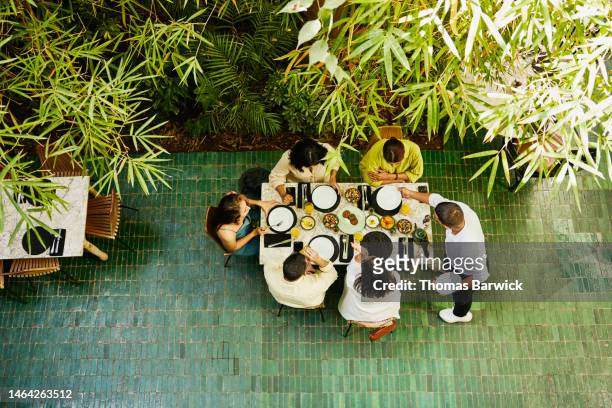 wide shot of waiter bringing plates to table of friends in restaurant - arab community life bildbanksfoton och bilder