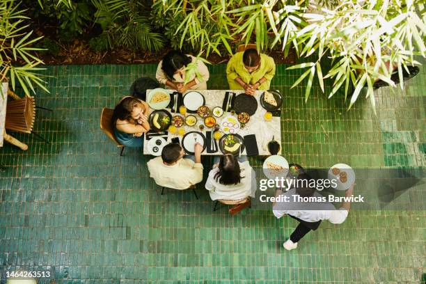 wide shot of waiter bringing food to table of friends in restaurant - waiter stock pictures, royalty-free photos & images