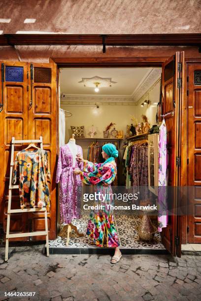 wide shot of business owner adjusting mannequin in front of boutique - tie dye stock pictures, royalty-free photos & images