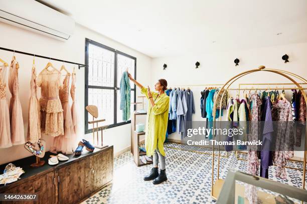 wide shot of woman taking photo of coat while shopping in boutique - fashion shoot stock-fotos und bilder