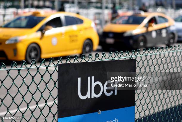 An Uber rideshare sign is posted nearby as taxis wait to pick up passengers at Los Angeles International Airport on February 8, 2023 in Los Angeles,...