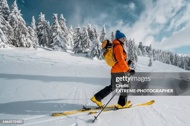 a fully equipped happy woman seen ski touring in the mountains surrounded by mesmerizing nature - skidsemester bildbanksfoton och bilder