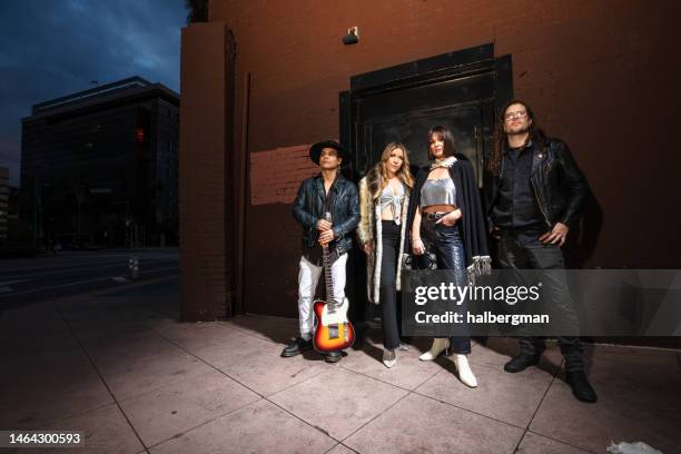 portrait of band standing by nightclub door - rockband stockfoto's en -beelden