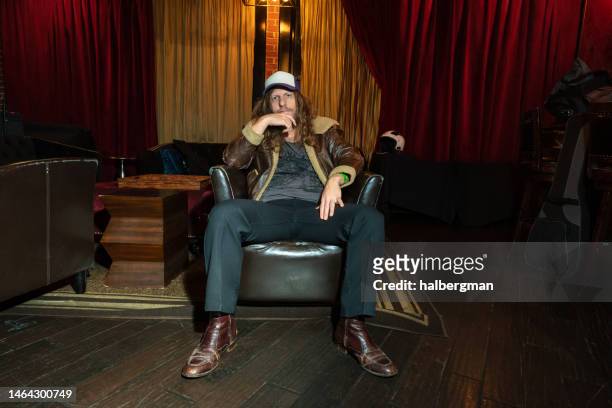 thoughtful, fashionable man sitting in armchair - in concert hollywood ca stock pictures, royalty-free photos & images