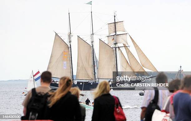 Visitors look at a sailing ship leaving the Baltic Sea port of Kiel-Schilksee during the opening day of the Kieler Woche sailing event on June 16,...