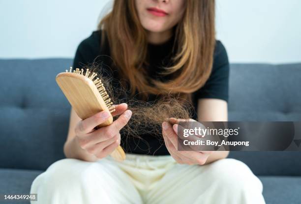 cropped shot of worried woman holding comb with hair loss after brushing her hair. - haarausfall stock-fotos und bilder